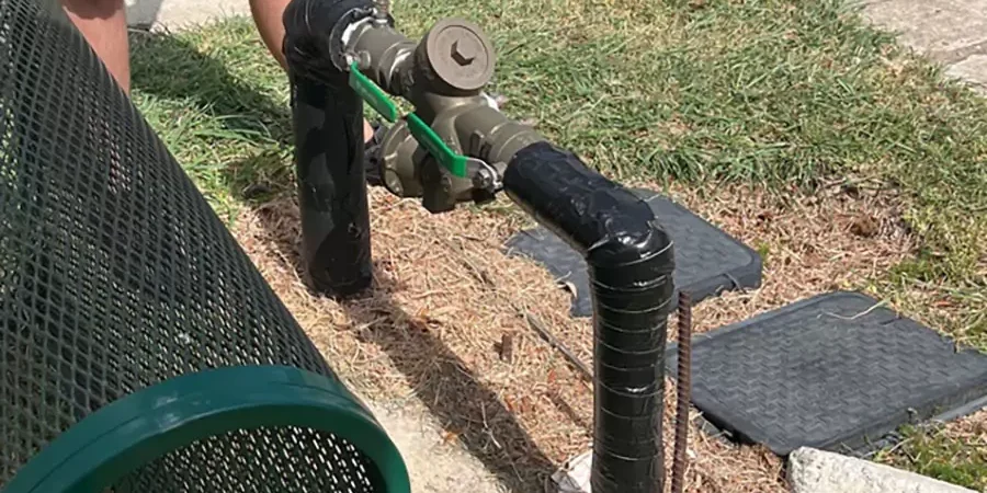 Technician installing a backflow prevention device in a residential sprinkler system